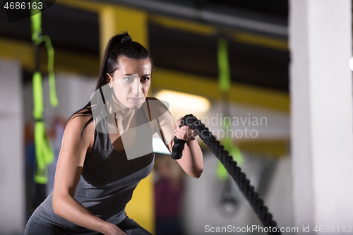 Image of athlete woman doing battle ropes cross fitness exercise