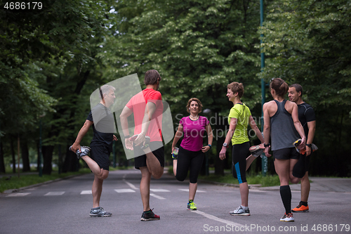 Image of runners team warming up and stretching before morning training