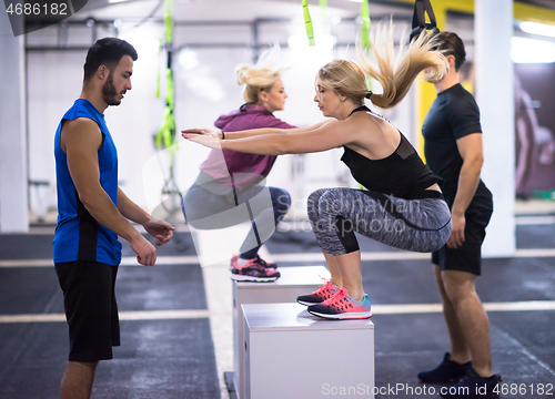 Image of athletes working out  jumping on fit box