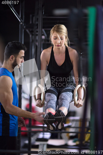 Image of woman working out with personal trainer on gymnastic rings