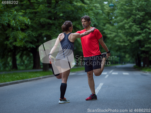 Image of runners team warming up and stretching before morning training