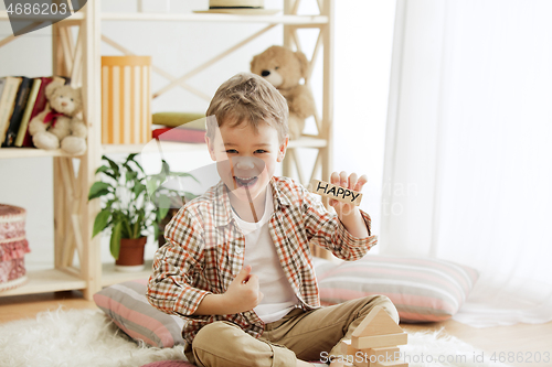 Image of Wooden cubes with word HAPPY in hands of little boy