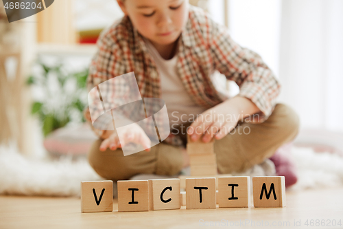 Image of Wooden cubes with word VICTIM in hands of little boy