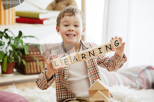 Image of Wooden cubes with word LEARNING in hands of little boy