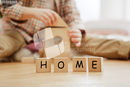 Image of Wooden cubes with word HOME in hands of little boy