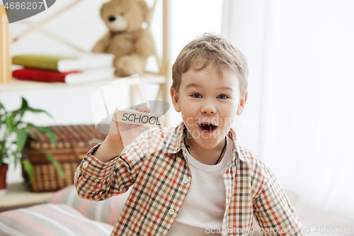 Image of Wooden cubes with word SCHOOL in hands of little boy