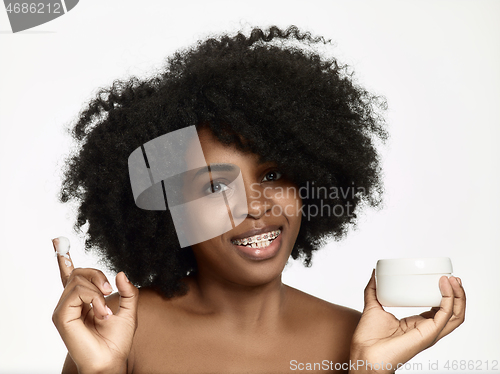 Image of Beautiful black african model with flawless skin smooth complexion applying moisturiser face cream to her cheek