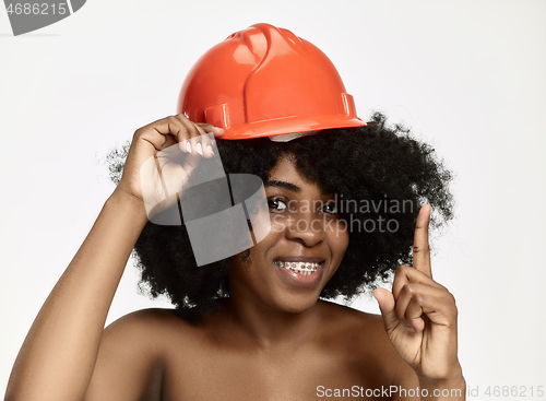 Image of Portrait of confident female worker in orange helmet