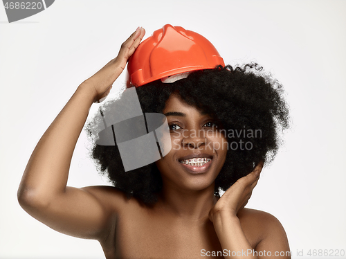 Image of Portrait of confident female worker in orange helmet