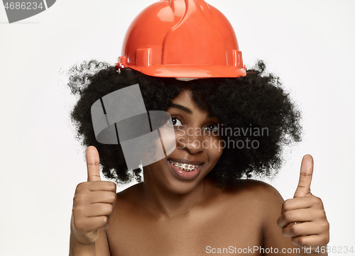 Image of Portrait of confident female worker in orange helmet