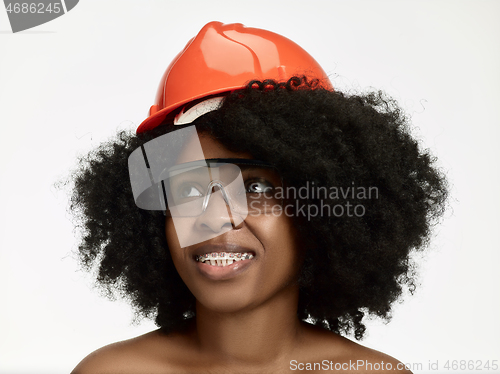 Image of Portrait of confident female worker in orange helmet