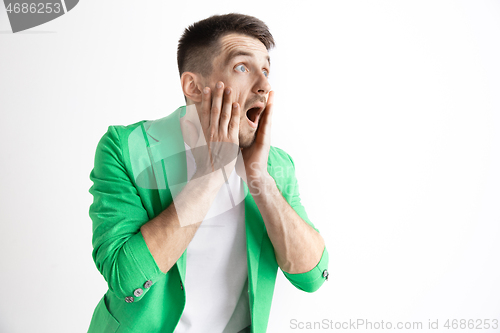 Image of The young attractive man looking suprised isolated on gray