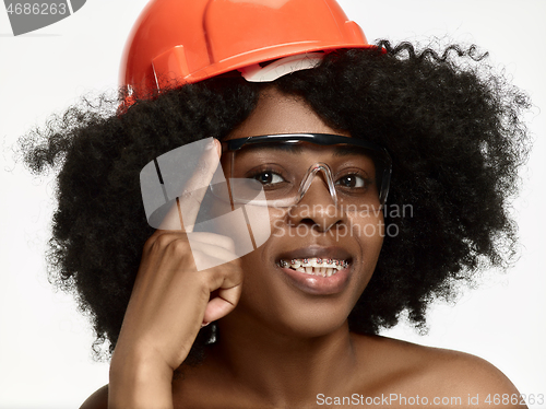 Image of Portrait of confident female worker in orange helmet