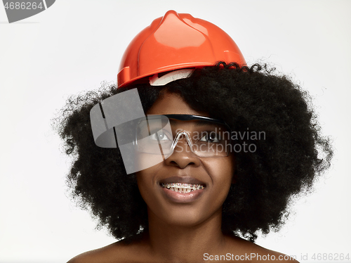 Image of Portrait of confident female worker in orange helmet