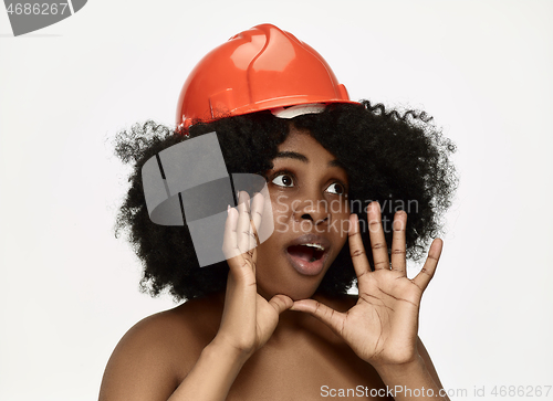 Image of Portrait of confident female worker in orange helmet