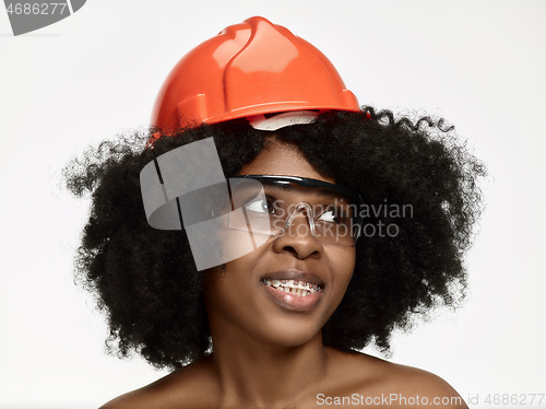 Image of Portrait of confident female worker in orange helmet