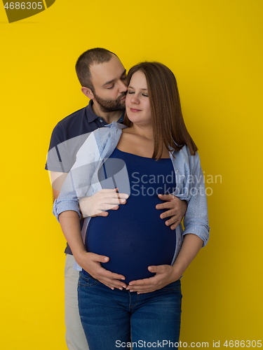 Image of pregnant couple  isolated over yellow background