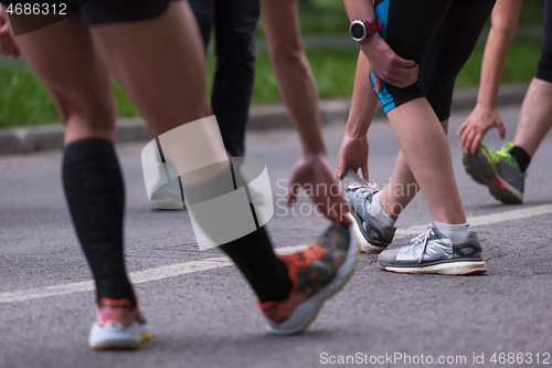 Image of runners team warming up and stretching before morning training