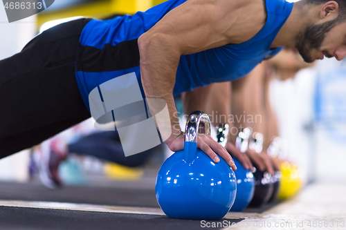 Image of young athletes doing pushups with kettlebells