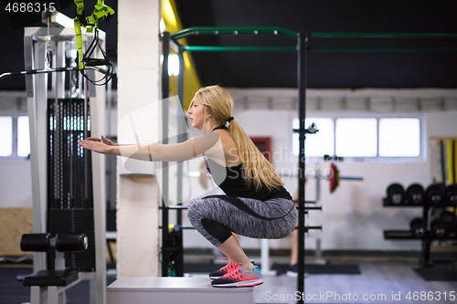 Image of woman working out  jumping on fit box