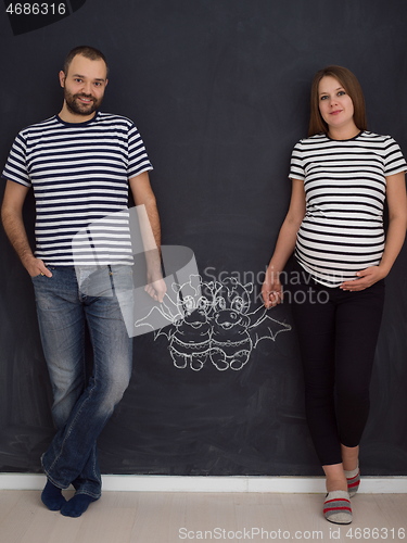 Image of pregnant couple drawing their imaginations on chalk board