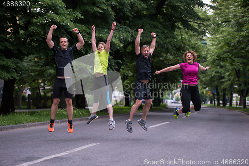 Image of runners team jumping in the air during  morning training