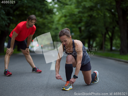 Image of sporty woman tying running shoes laces