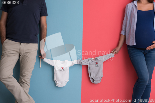 Image of young couple holding baby bodysuits