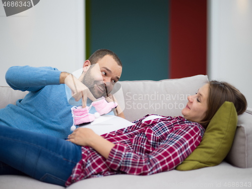 Image of young pregnant couple relaxing on sofa