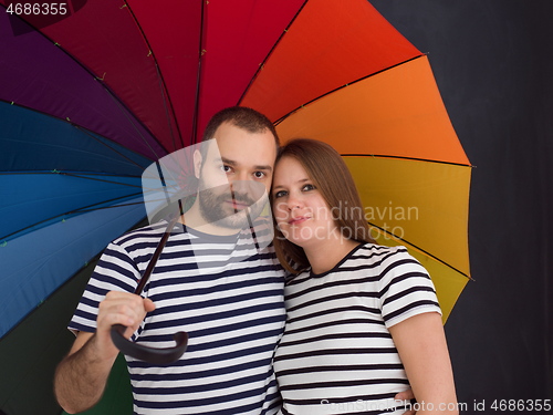 Image of pregnant couple posing with colorful umbrella