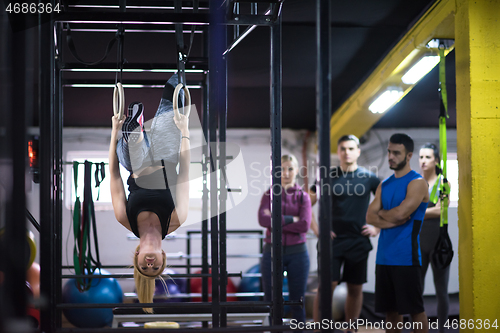 Image of woman working out with personal trainer on gymnastic rings