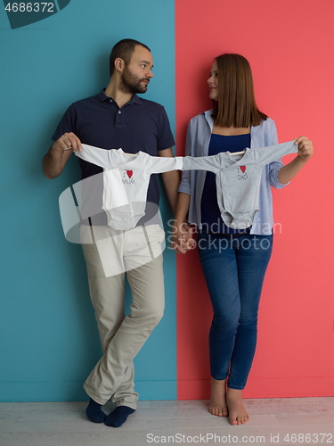 Image of young couple holding baby bodysuits