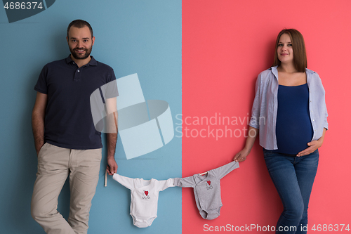 Image of young couple holding baby bodysuits