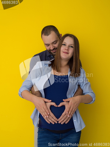 Image of pregnant couple  isolated over yellow background