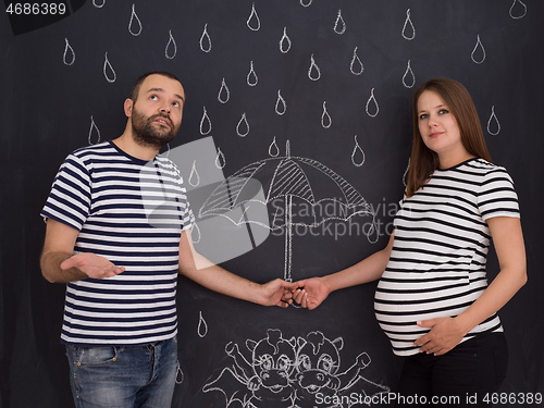 Image of pregnant couple drawing their imaginations on chalk board