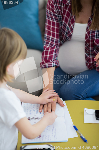 Image of daughter painting nails to her pregnant mom