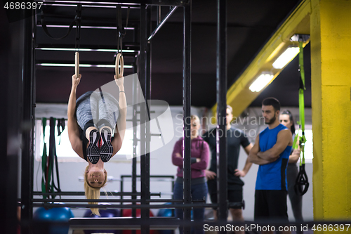 Image of woman working out with personal trainer on gymnastic rings