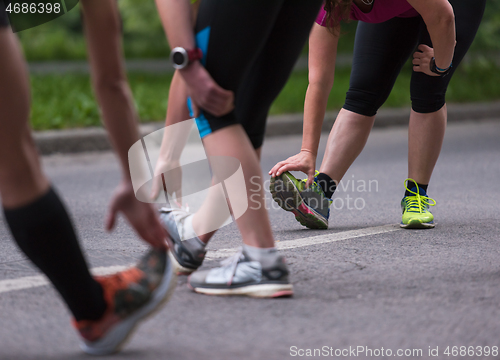 Image of runners team warming up and stretching before morning training