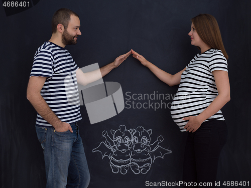 Image of pregnant couple drawing their imaginations on chalk board