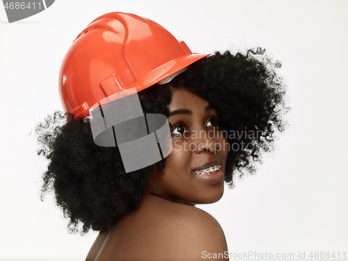 Image of Portrait of confident female worker in orange helmet