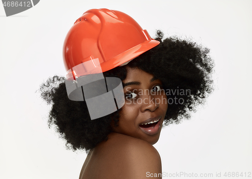 Image of Portrait of confident female worker in orange helmet