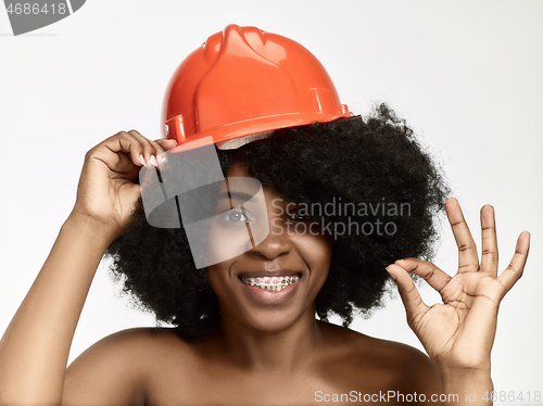 Image of Portrait of confident female worker in orange helmet