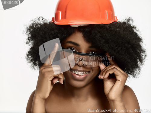 Image of Portrait of confident female worker in orange helmet