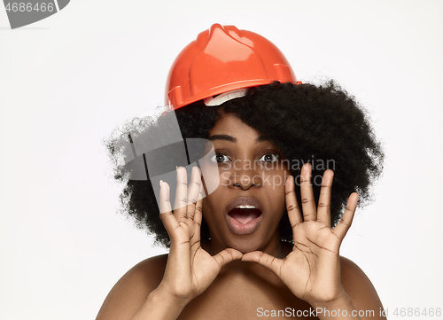 Image of Portrait of confident female worker in orange helmet