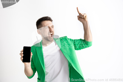 Image of Young handsome man showing smartphone screen and signing OK isolated on gray background