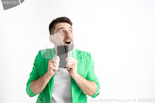 Image of Young handsome man showing smartphone screen and signing OK isolated on gray background