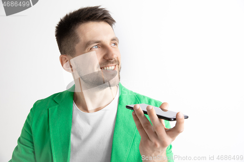 Image of Indoor portrait of attractive young man holding smartphone