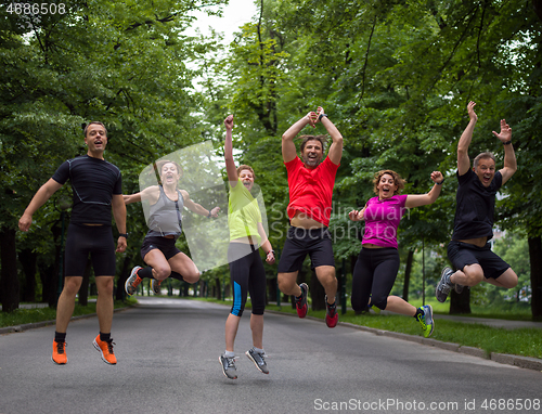 Image of runners team jumping in the air during  morning training