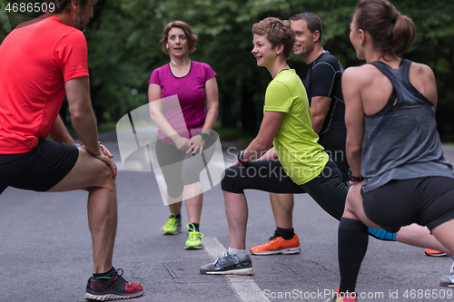 Image of runners team warming up and stretching before morning training