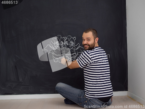 Image of future dad drawing his imaginations on chalk board